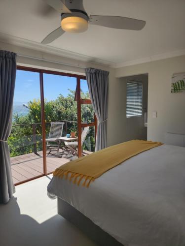 a bedroom with a bed and a balcony with a view at The Tides in Simonʼs Town