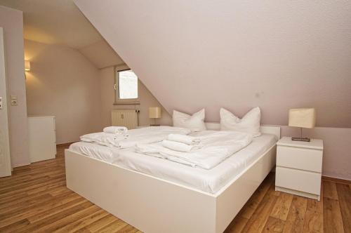 ein großes weißes Bett mit weißer Bettwäsche und Kissen in der Unterkunft strandnah mit Balkon, gratis Nutzung vom AHOI Erlebnisbad und Sauna in Sellin - Strandhaus Mönchgut FeWo21 in Lobbe