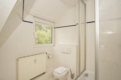 ein weißes Bad mit einem WC und einem Fenster in der Unterkunft strandnah mit Balkon, gratis Nutzung vom AHOI Erlebnisbad und Sauna in Sellin - Strandhaus Mönchgut FeWo21 in Lobbe