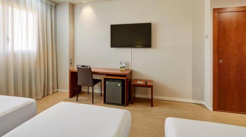 a hotel room with a desk and a tv at Sercotel Ciutat de Montcada in Montcada i Reixac