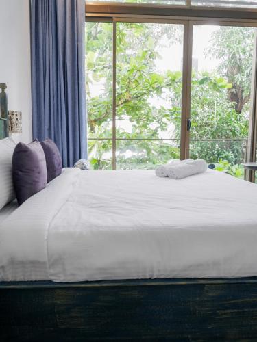 a large bed with two towels on it in front of a window at Dia Hotels and Homes Nerul Goa - Villas and Apartments in Nerul