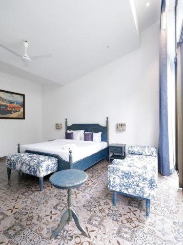 a bedroom with a bed and two chairs at Dia Hotels and Homes Nerul Goa - Villas and Apartments in Nerul