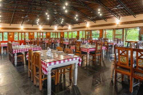 a dining room with tables and chairs and windows at Magnolia Estates & Resorts in Virajpet