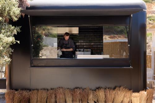 a man standing in a window of a building at Golden Milos Beach Ηouse by Domotel in Provatas