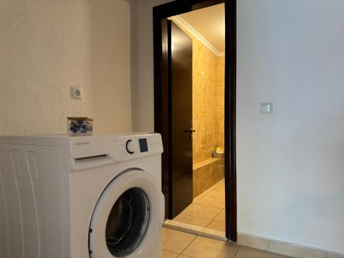 a white washing machine in a bathroom with a door at Katoi - Traditional House in Panayia