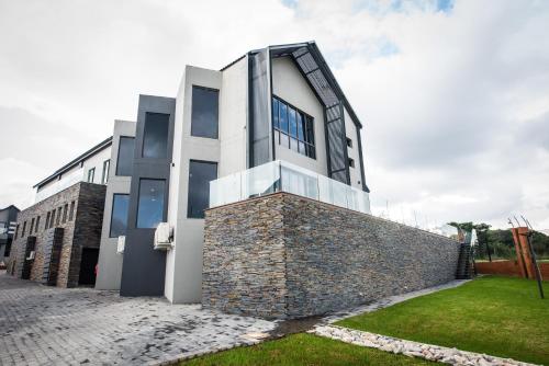 un edificio con un muro di pietra accanto a un edificio di Acacia Villas Blue Hills - 3 Bedroom Luxury Villa a Midrand