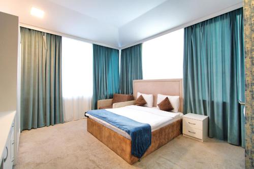 a bedroom with a bed with blue curtains at Sunday Hotel & Apartments in Baku