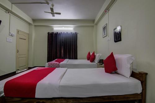 a bedroom with two beds with red pillows at Hotel O V Knot Residency in Port Blair