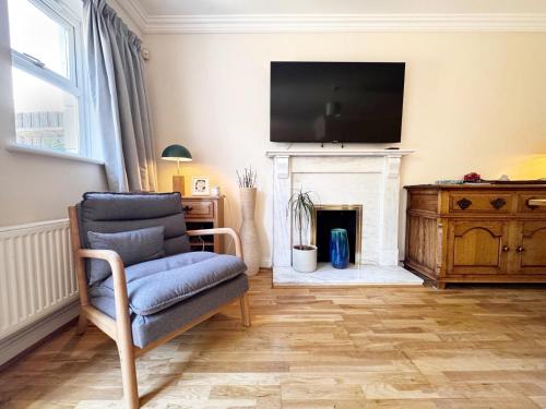 a living room with a chair and a tv over a fireplace at Spacious 4-bedroom townhouse in the city center with free parking in Oxford
