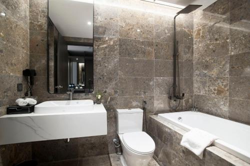 a bathroom with a toilet and a tub and a sink at GrandView Hotel & Residence Hanoi in Hanoi