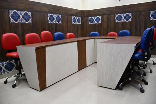 a conference room with two tables and red chairs at Hotel Sindhu in Bareilly