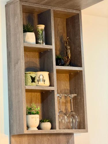 a wooden cabinet filled with glasses and potted plants at Royal Apartmani 1 in Paraćin