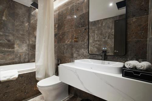 a bathroom with a sink and a toilet and a tub at GrandView Hotel & Residence Hanoi in Hanoi