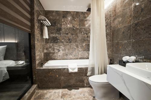 a bathroom with a tub and a toilet and a sink at GrandView Hotel & Residence Hanoi in Hanoi