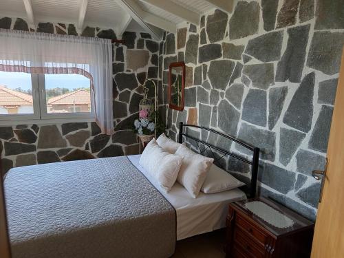 ein Schlafzimmer mit einem Bett und einer Steinwand in der Unterkunft Blue Paradise Villa in Karianí