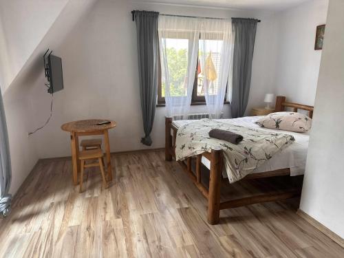 a bedroom with a bed and a table and a window at Willa Agma in Zakopane