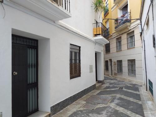 an alley with white buildings and a black door at Gomez City Centre in Málaga
