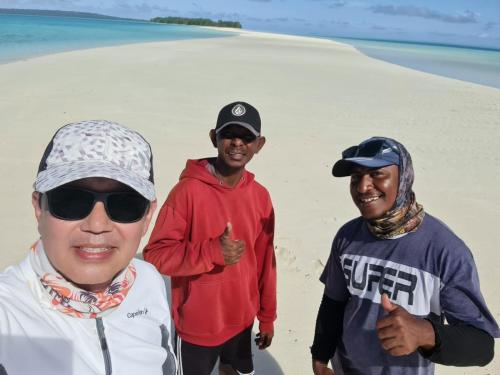 a group of three men standing on the beach at Amaro Homestay in Nuhu Tawun