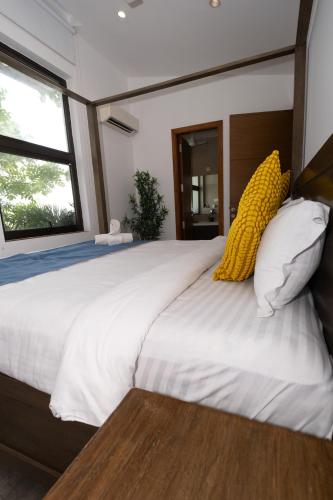 a bedroom with a large white bed with yellow pillows at Dia Hotels and Homes Nerul Goa - Villas and Apartments in Nerul