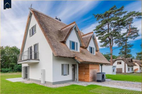 a large white house with a thatched roof at Fischerdorf DDH Hafftraum in Zirchow