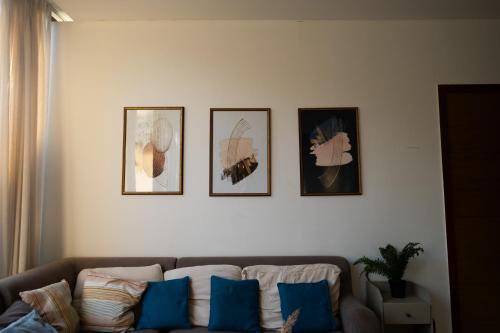 a living room with a couch and four pictures on a wall at Dia Hotels and Homes Nerul Goa - Villas and Apartments in Nerul