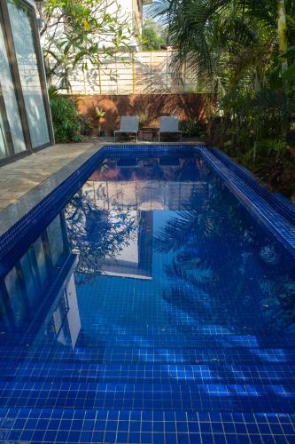 a blue swimming pool with two chairs in it at Dia Hotels and Homes Nerul Goa - Villas and Apartments in Nerul
