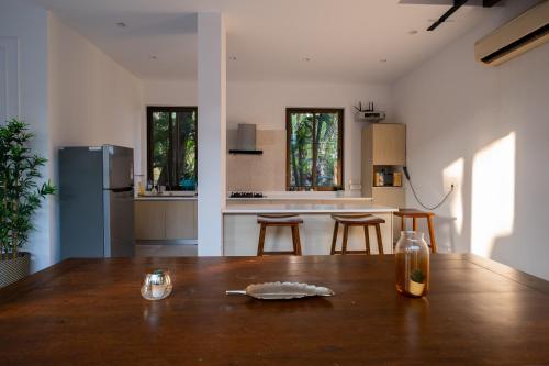 a kitchen with a wooden table and a kitchen with a refrigerator at Dia Hotels and Homes Nerul Goa - Villas and Apartments in Nerul