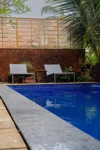 a pool with two chairs and a table next to it at Dia Hotels and Homes Nerul Goa - Villas and Apartments in Nerul