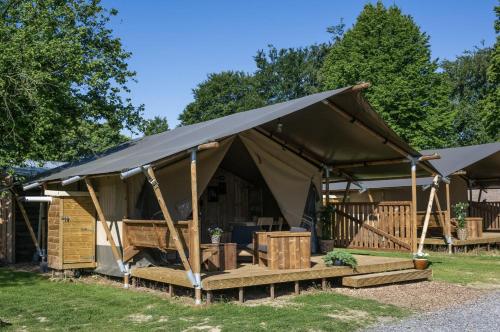 a tent with a black canopy on the grass at Camping Mareveld in Schimmert