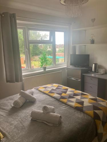 a bedroom with two towels on a bed with a window at Welcoming Home Close to Transport Links in Thornton Heath