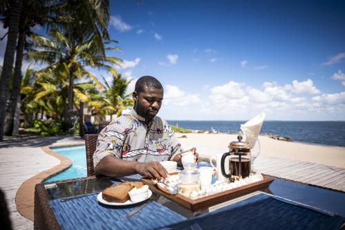 a man sitting at a table with a tray of food at Castelo Beach Resort in Inhambane