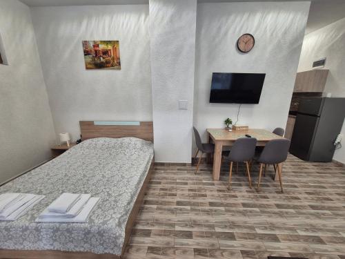 a hotel room with two beds and a table and a television at Студио Лазур с Безплатен Паркинг in Pomorie