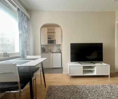 a living room with a tv and a table and a kitchen at Helsinki Punavuori Studio in Helsinki