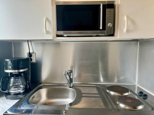 a kitchen counter with a sink and a microwave at Helsinki Punavuori Studio in Helsinki