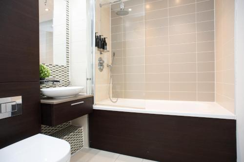 a bathroom with a tub and a sink and a toilet at Peaceful, cosy - modern 2 Bedroom entire Flat in Canary Wharf Close to the 02 in London