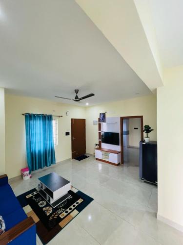 a living room with a blue couch and a tv at Harmony residency in Kammasandra