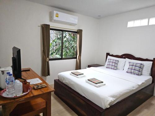 a bedroom with a bed with a desk and a window at Samet Bellhouse in Ko Samed