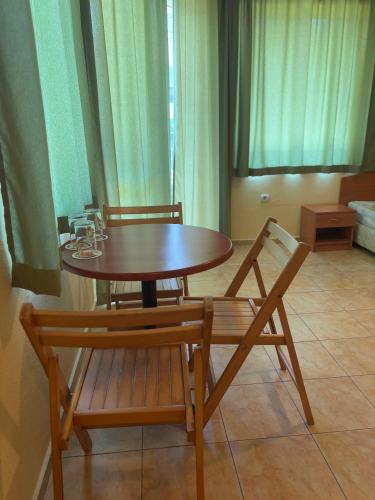 a wooden table and two chairs and a table with glasses on it at Семеен хотел САМИ in Kranevo