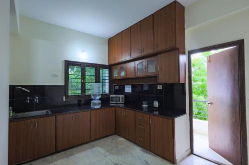 a large kitchen with wooden cabinets and a door at Hotel Athome & Serviced Apartments by Deccan Serai Hotels in Hyderabad