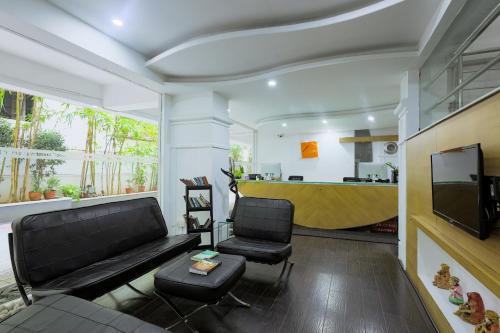 a living room with a couch and two chairs and a tv at Hotel Athome & Serviced Apartments by Deccan Serai Hotels in Hyderabad