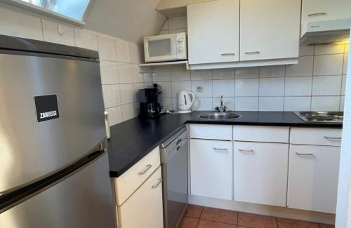 a kitchen with a stainless steel refrigerator and white cabinets at Vakantiepark Bergsehaak in Haaksbergen