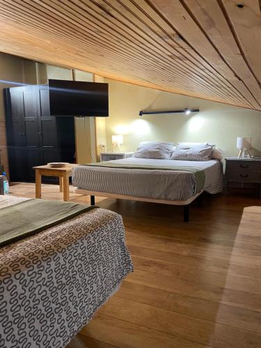 a bedroom with two beds and a wooden ceiling at Casa Rural Jim Morrison in Linares de Riofrío