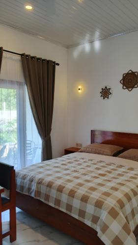 a bedroom with a bed with a checkered blanket at Cena Homestay in Mantaak