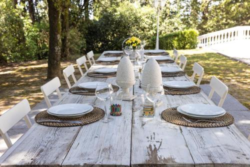 a long wooden table with white plates and wine glasses at Villa Rinaldi in Montespertoli