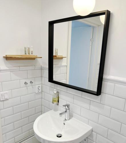 a white bathroom with a mirror and a sink at Adas Hotell in Östhammar