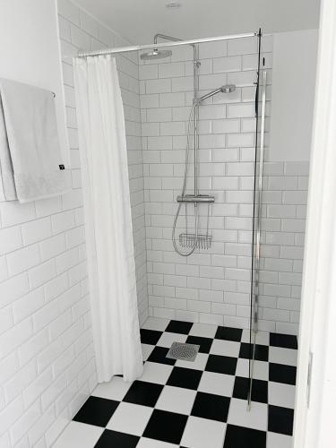 a bathroom with a shower with a black and white checkered floor at Adas Hotell in Östhammar