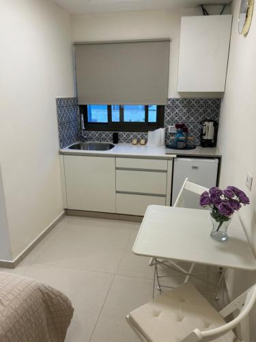 a white kitchen with a vase of flowers on a table at Guest Suite for you! Our location is bet Shemesh in Mashabbe Sade