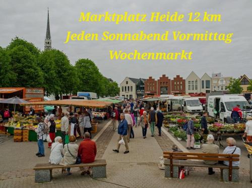 a group of people sitting on benches at an outdoor market at Bett und Bike Dithmarschen in Epenwöhrden