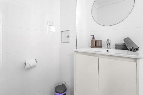 a white bathroom with a sink and a mirror at 2-Bedroom House Hoolloomooloo Good for 6 Guests in Sydney