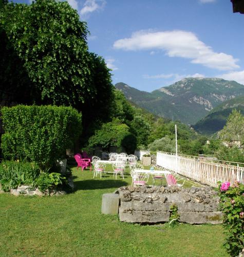 a group of tables and chairs in a yard with mountains at Le Mirval in La Brigue